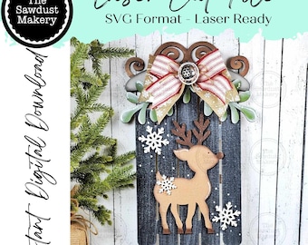 May include: A wooden Christmas sled with a reindeer and snowflake design. The sled is painted dark gray with a light brown reindeer and white snowflakes. A red and white striped bow and green leaves adorn the top. Text on the image reads "Laser Cut File".