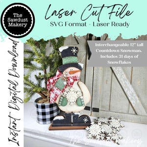 May include: A laser cut file digital download for a 12-inch tall interchangeable countdown snowman. The snowman features a black top hat, a red and white plaid scarf, green mittens, and a carrot nose. It includes 31 wooden snowflake pieces.