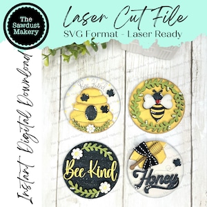 May include: Four round wooden signs with bee-themed designs. The signs feature a beehive, a bee, a wreath of flowers, and the words "Bee Kind" and "Honey".