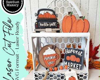 Op de afbeelding: Een digitale bestandsset voor lasersnijden met herfstdecoratie. Bevat een zwarte vrachtwagen met pompoenen, twee oranje pompoenen, een rond bord met Pumpkin Spice, een vierkant bord met Harvest Market en een kralenslinger met pompoenthema.