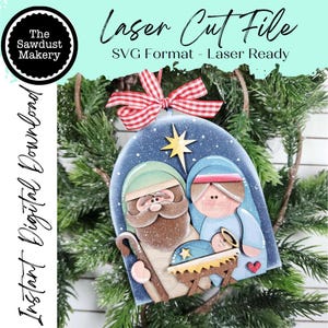 May include: A laser-cut Christmas ornament featuring a nativity scene with Joseph, Mary, and baby Jesus. The ornament is painted in soft colors and has a red and white checkered bow. The text "Laser Cut File" is visible.
