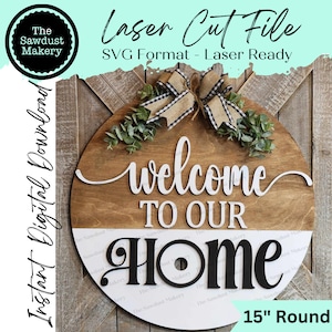 Peut inclure: Panneau rond en bois avec l'inscription "welcome to our home" en blanc et noir. Le panneau mesure environ 38 cm de diamètre et comporte un nœud décoratif et de la verdure. Fichier de découpe laser au format SVG.