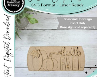 May include: A laser-cut wooden sign insert featuring two pumpkins, one with a leaf detail, and the text "hello FALL". The design is a flat, light brown material intended for a seasonal door sign, with the text clearly visible in a script and block font.