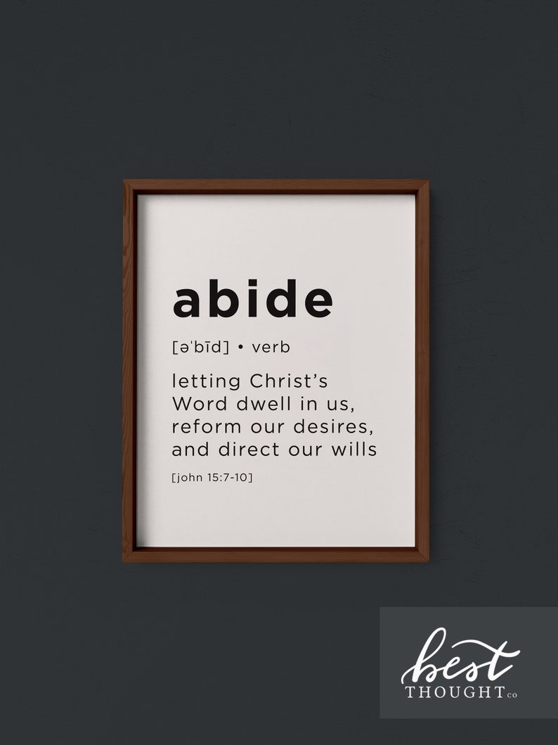 May include: A black and white printable wall art print with the word "abide" defined as "letting Christ's Word dwell in us, reform our desires, and direct our wills" with a scripture reference from John 15:7-10. The print is framed in a brown wood frame.