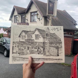 Pode incluir: Um desenho a caneta e tinta preta e branca do pub "The Mouse" é exibido em frente ao pub real. O desenho mostra o exterior do pub, incluindo a placa e os detalhes arquitetônicos. O céu está nublado.