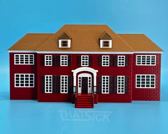 May include: A miniature red house with a brown roof and white window frames. The house has a symmetrical design with a central entrance and the text "THATSICK" at the bottom. The background is a solid blue.