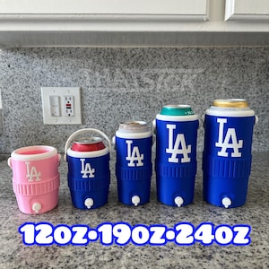 May include: A range of insulated beverage coolers in blue and pink, with white "LA" logos. Sizes include 120oz, 190oz, and 240oz. Each cooler has a tap for dispensing drinks. The coolers are designed to keep beverages cold.