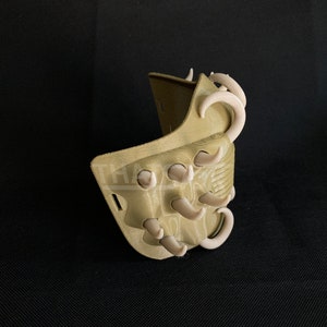 May include: A tan-colored, 3D-printed mask with curved, off-white accents. The mask has a textured surface and a series of protruding, tooth-like shapes. The design suggests a fantasy or cosplay theme.