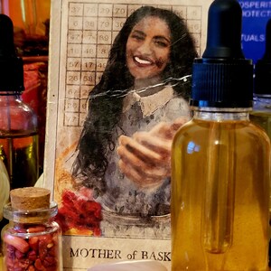 May include: An assortment of spiritual items, including a glass bottle with a dropper, a small jar with a cork, a rose quartz stone, and a card with the text "MOTHER of BASK". The bottle contains a golden liquid.