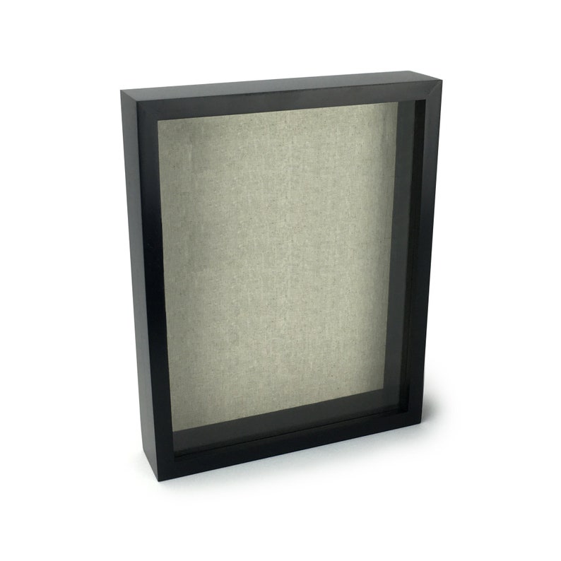 May include: A black shadow box frame with a light grey fabric backing.