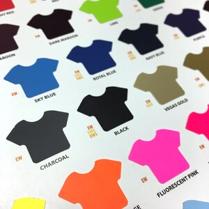 May include: A color chart of t-shirt colors, showing different shades of blue, red, green, yellow, black, pink, orange, and grey. The chart is labeled with the color names, such as "Sky Blue", "Royal Blue", "Navy Blue", "Black", "Charcoal", "Fluorescent Orange", "Fluorescent Pink", and "Vegas Gold".