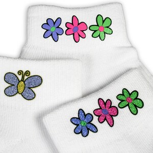 May include: A pair of white ankle socks with colourful embroidered flowers and a butterfly. The socks have a ribbed texture.