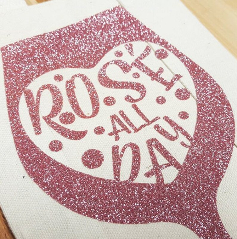 May include: A pink glitter wine glass tote bag with the text "Rose All Day" in a heart shape.