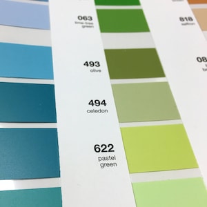 May include: Color chart featuring a range of green and blue hues, with names and numbers printed alongside each color swatch. Shades include olive, celadon, and key lime pie. The chart is for design or reference.