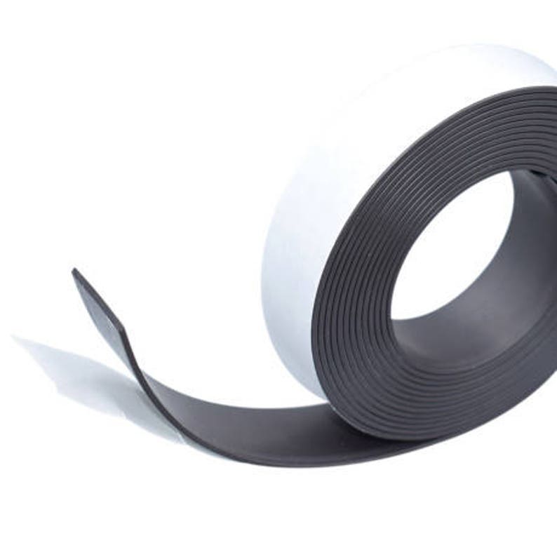 Pu&ograve; includere: Un rotolo di nastro magnetico nero con retro bianco. Il nastro &egrave; arrotolato e una parte del nastro &egrave; srotolata.
