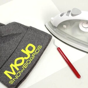 May include: A gray beanie with the yellow text "Mojo Snowboards" on the side. An iron and a red tool are also in the image.