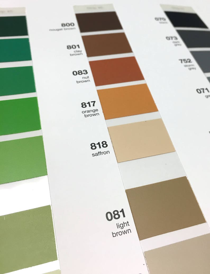 May include: A color chart with various shades of brown, green, and gray. The chart includes color swatches labeled with numbers and names like "nut brown," "orange brown," and "saffron." The image is well-lit, showcasing the different hues and tones.