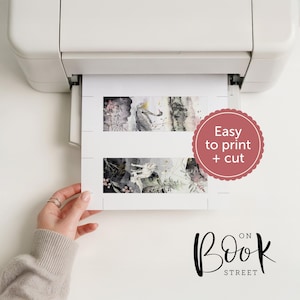 May include: A white printer outputting a sheet of paper with two rectangular bookmarks featuring watercolor illustrations of a wolf and forest elements. A pink scalloped circle contains the text Easy to print + cut. The logo Book on Street is visible.