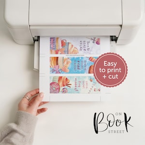 May include: A white printer outputting a sheet of paper containing three vertical bookmarks with watercolor illustrations of cupcakes and sweets. The text reads Time to read & relax, When in doubt, read a book!, and Life is short, keep reading!
