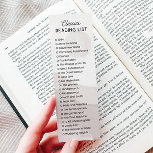 Könnte beinhalten: Eine weiße Karte mit einer Liste klassischer Bücher zum Lesen. Die Karte hat einen schwarzen Kreis um jeden Buchtitel und ein schwarzes Häkchen neben jedem Titel. Die Karte ist mit "Klassiker-Leseliste" betitelt.