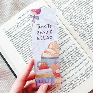 K&ouml;nnte beinhalten: Ein farbenfrohes Lesezeichen mit einem verspielten Design mit Cupcakes und Erdbeeren. Das Lesezeichen tr&auml;gt den Text "Time to Read & Relax" in schwarzer Schrift.
