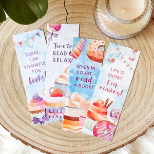 May include: Four colorful bookmarks with watercolor illustrations of cupcakes, donuts, and candy. The bookmarks feature inspirational quotes about reading, such as "Today, I am thankful for books!" and "Life is short. Keep reading!"