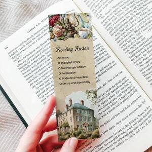 Könnte beinhalten: Ein rechteckiges Lesezeichen aus Papier im Vintage-Stil mit einem Blumenarrangement, einer Teetasse und einer Laterne am oberen Rand. Der Text Reading Austen steht über einer Liste der Titel: Emma, Mansfield Park, Northanger Abbey, Persuasion, Pride and Prejudice und Sense and Sensibility. Unten ist ein großes Haus abgebildet.