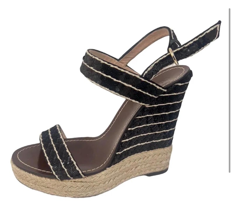 May include: Black wedge sandals with a woven jute sole and black fabric straps. The straps are accented with white trim. The wedge heel is approximately 4 inches high.