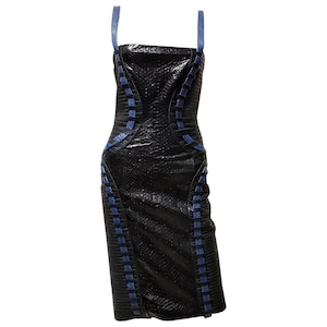May include: A black, textured sheath dress with blue accents. The dress features blue straps and blue woven detailing along the sides and front. The dress is a knee-length, bodycon style.