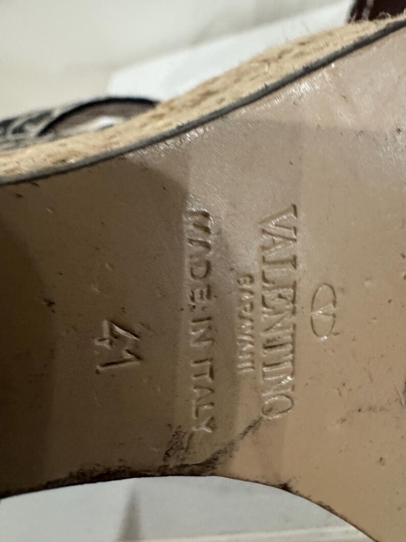 May include: Close-up of the sole of a shoe. The shoe is marked "VALENTINO GARAVANI" and "MADE IN ITALY". The size is marked as "41". The sole is a light brown color.