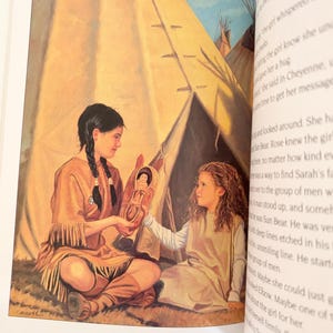 May include: An illustration in a book showing two children sitting in front of a tan teepee. One child with dark braided hair wears a tan fringed tunic and holds a small cradleboard with a doll inside, offering it to a child with curly hair.