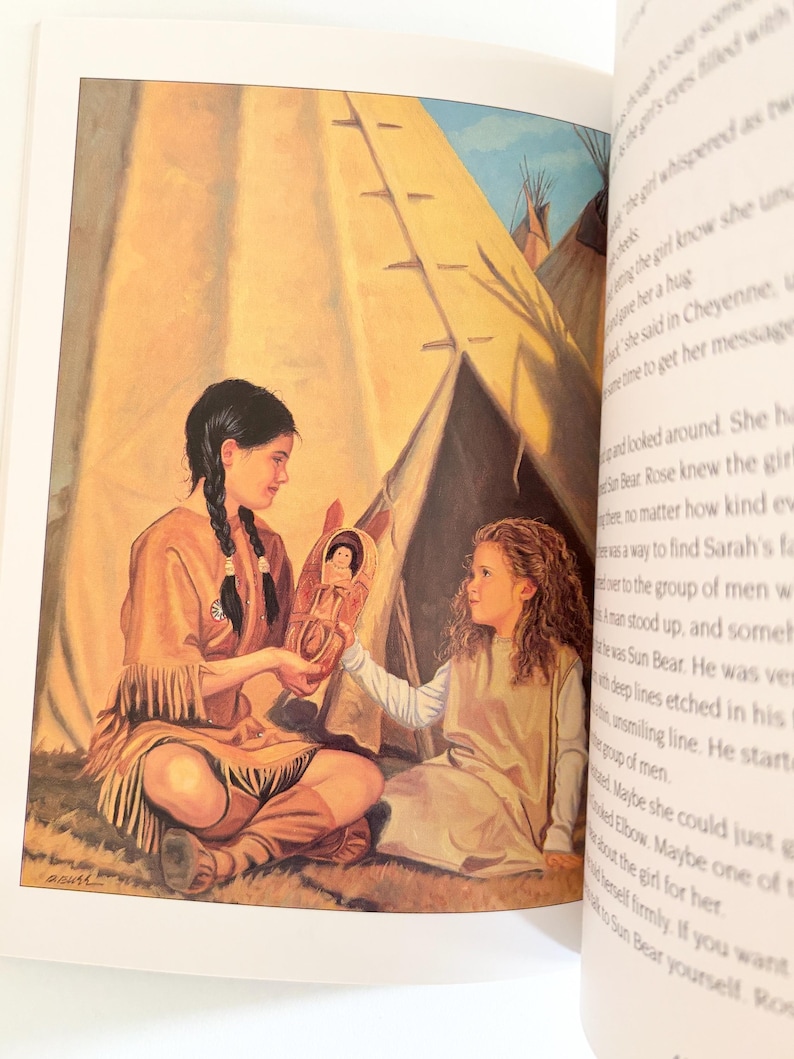 May include: An illustration in a book showing two children sitting in front of a tan teepee. One child with dark braided hair wears a tan fringed tunic and holds a small cradleboard with a doll inside, offering it to a child with curly hair.