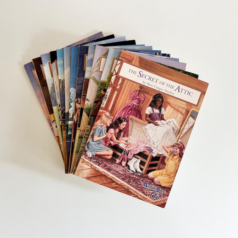 May include: A collection of Magic Attic Club books fanned out, with the front cover titled The Secret of the Attic by Sheri Cooper Sinykin. The cover illustration depicts three children interacting with a trunk filled with clothing and accessories.