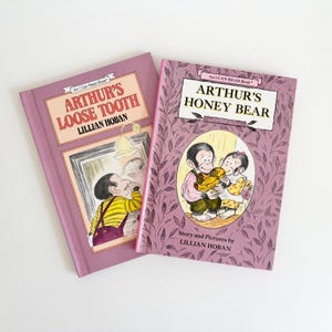 May include: Two purple children's books with the title "Arthur's Loose Tooth" and "Arthur's Honey Bear". Both books are part of the "I Can Read Book" series and are illustrated by Lillian Hoban.
