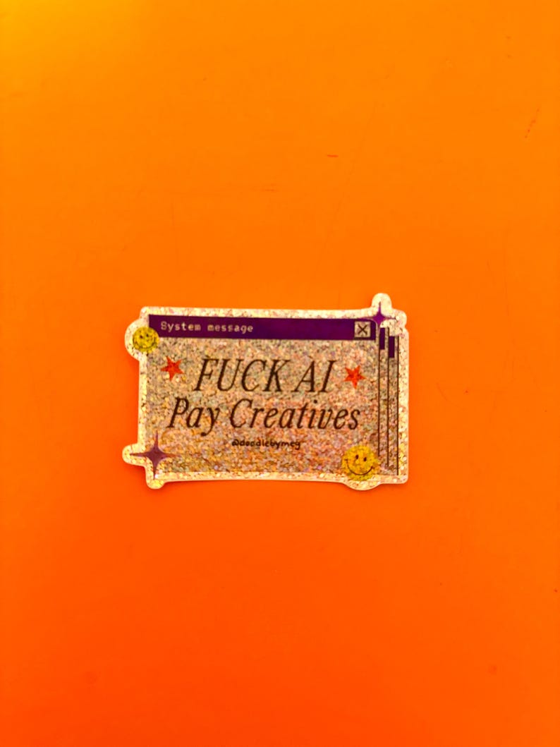 May include: A rectangular holographic sticker featuring a purple header with the text System message and an X icon. The center text reads FUCK AI Pay Creatives in black, flanked by red stars. Two yellow smiley faces and purple star icons decorate the corners.