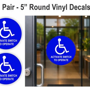 Op de afbeelding: Set van twee ronde blauwe vinylstickers van 12,7 cm. Elke sticker heeft een wit rolstoelsymbool en de tekst "ACTIVATE SWITCH TO OPERATE". Eén sticker is op een glazen deur. De andere twee stickers worden apart getoond.