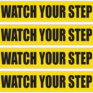 May include: Four yellow signs with black text that reads "Watch Your Step".