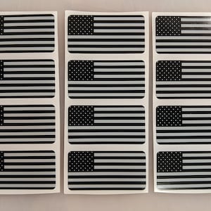 以下が含まれることがあります： 黒と白のアメリカ国旗のステッカーが12枚。ステッカーは長方形で、光沢のある仕上げです。