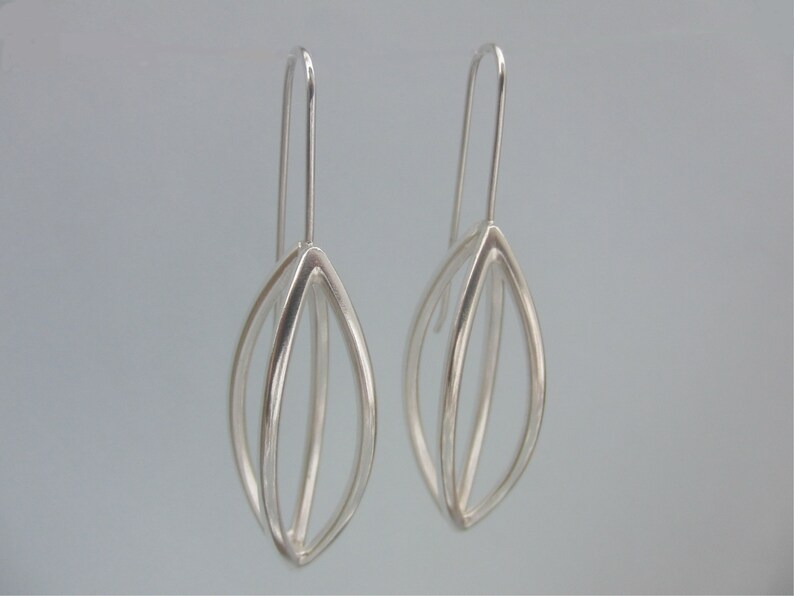 May include: A pair of silver dangle earrings with a geometric leaf design.