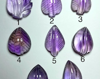 Könnte beinhalten: Eine Sammlung von acht geschnitzten Amethyst-Edelsteinblättern. Jedes Blatt hat eine andere Form und Größe mit komplizierten Aderdetails. Die Edelsteine reichen in der Farbe von hell bis tiefviolett.
