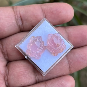 K&ouml;nnte beinhalten: Ein Paar rosa Rosen-Ohrringe, die in einer durchsichtigen Plastikbox liegen.