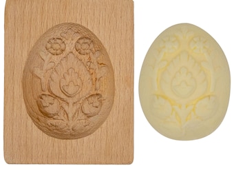 May include: A wooden mold for making butter eggs, with a floral design. The mold is shown next to a finished butter egg.