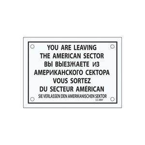 Könnte beinhalten: Ein weißes Schild mit schwarzem Text und einem schwarzen Kreis an jeder Ecke. Das Schild lautet "You are leaving the American Sector" in Englisch, Russisch, Französisch und Deutsch. Das Schild enthält auch den Text "U.S. Army".