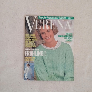 Op de afbeelding: Een uitgave van het tijdschrift Verena uit maart 1991 met een persoon in een lichtgroene kabeltrui. De cover bevat de tekst Mode-Maschen-Ideen, Verena, Neue Farben, Weiche Garne, Schöne Muster und Motive für Pullis & Strickjacken, Schick in den Frühling, Kreative Handarbeiten Jede Menge Gemüse en Fertigschnitt.