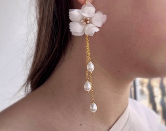 May include: White flower dangle earrings with a gold chain and three pearl accents.