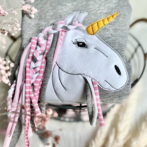 Puede incluir: Una sudadera gris con una aplicaci&oacute;n de unicornio blanco. El unicornio tiene una crin trenzada rosa y gris y un cuerno amarillo.