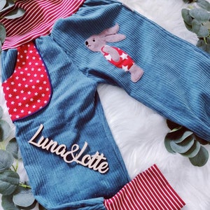 May include: Blue corduroy pants with red and white striped cuffs and waistband. The pants have a red pocket with white stars and a felt bunny applique with red and white stars.