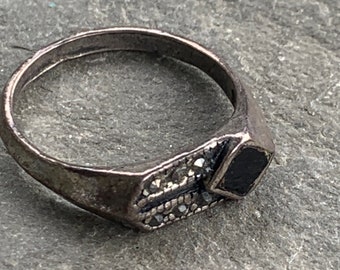 May include: A silver ring with a black stone and a band decorated with small, sparkling stones.