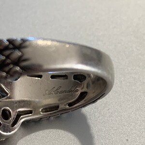 May include: Close-up of the inside of a silver ring with the inscription "A. Candela" on the band.