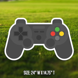May include: A black video game controller with white buttons and a green, red, and yellow button layout. The controller is 24 inches wide and 14.75 inches tall. SIZE: 24" W x 14.75" T
